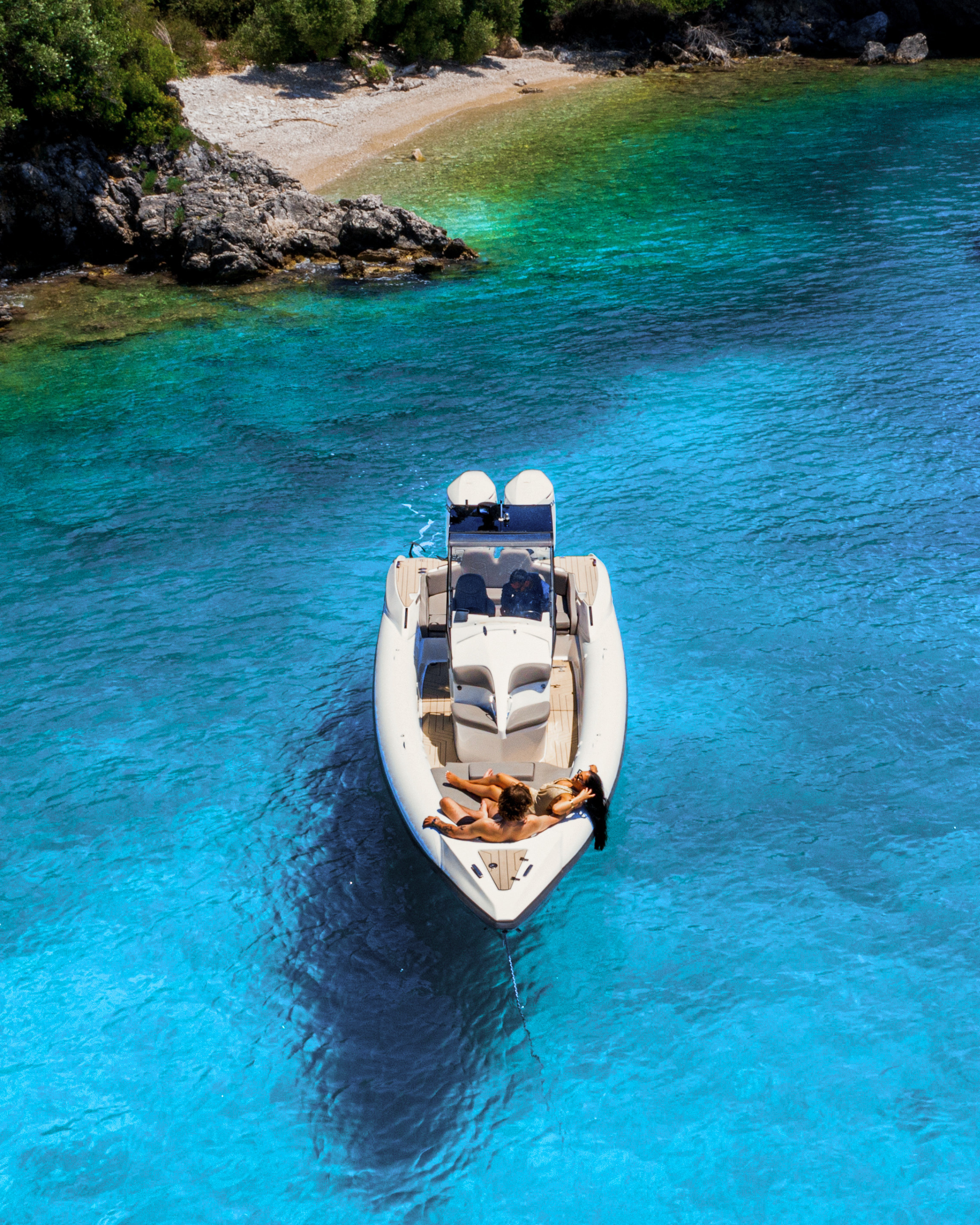 Boat on a clear blue sea with a rocky coastline